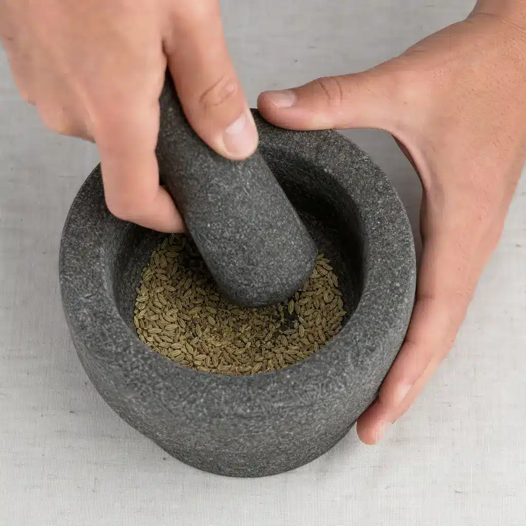 Manos machacando ligeramente semillas de hinojo en un mortero de piedra